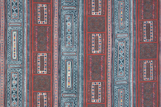 A vibrant textile with vertical stripes and geometric patterns featuring diamonds, florals, and intricate borders in red, blue, white, and yellow.