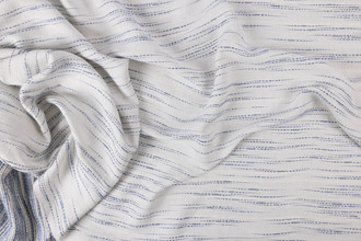 Indigo colourway of the Nendo Collection wide-width curtain fabric shown in a scrunch detail shot, highlighting the linen and cotton mix with multicoloured woven stitching and rain-inspired texture.