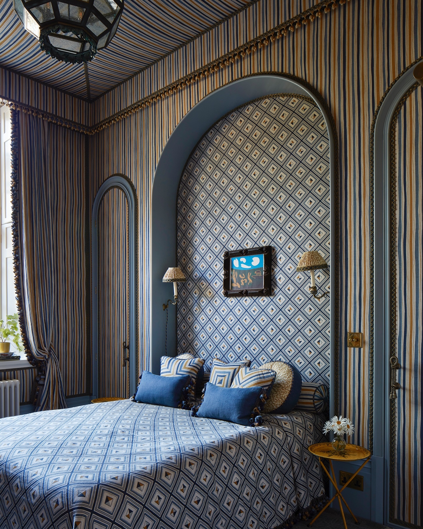 A contemporary take on royal grandeur, this bedroom by MBDS features Boundary in Ochre cascading from a canopy, layered with Fresco cushions in deep indigo. Dramatic, elegant, and unapologetically cool—a space where soft structure and graphic print reign.