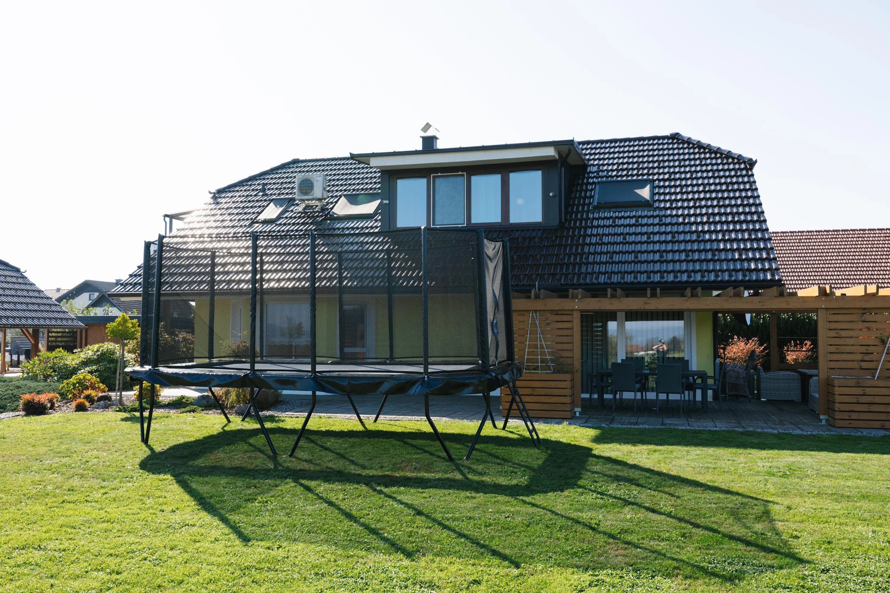 Akrobat Primus Challenger PLUS 17x10ft trampoline in a garden in front of a house
