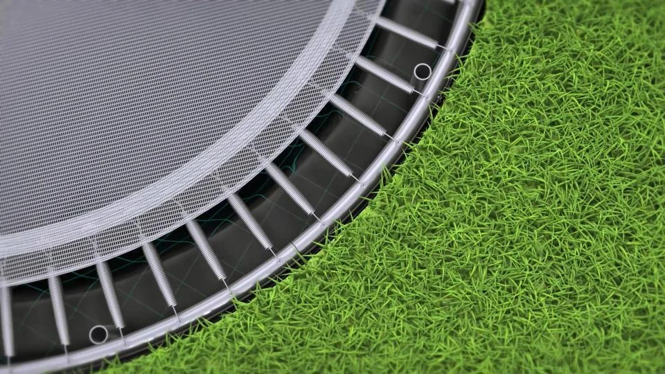 Close-up of the Akrobat Primus Flat jumping mat edge and springs, set flush with the lawn