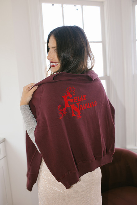 The Great the College Sweatshirt Feliz Navidad draped on back