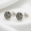 Moon Pentacle: Pair of silver stud earrings resting on a white background with a clear reflection