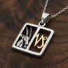 Capricorn pendant: Silver and gold horoscope necklace resting on a rich, dark wooden surface at our Witchcraft store