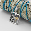 Horoscope pendant: Silver and gold Aries necklace resting on a bundled sage smudge stick with blue string