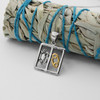 Mystical Cancer necklace draped delicately over a bundle of dried sage, showcasing the high-quality .925 sterling silver and gold craftsmanship