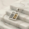 Libra pendant zodiac jewelry, displaying a two-tone silver and gold horoscope design resting elegantly on white marble steps