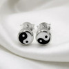 Yin Yang post earrings for women, featuring a classic black and white small design resting gracefully on smooth, draped white silk fabric