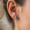 Egyptian ankh earrings for women, showcasing a polished sterling silver finish and a striking amethyst center, worn elegantly on a model's earlobe for a refined, minimalist look