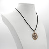 Greenman necklace displayed on a white jewelry bust, demonstrating the hanging scale and the black cord of this bronze pagan pendant