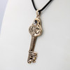 Witchy jewelry close-up angled to the right, emphasizing the polished gold-bronze finish of the witches key necklace against a clean white background