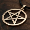 Bronze pentagram necklace at our witchcraft store resting flat on a rich dark wood grain surface, highlighting the smooth, interlocking gold pentacle star