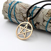 Wicca jewelry showcasing a large gold pentagram necklace draped elegantly over a bundled white sage smudge stick at our pagan jewelry store