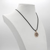 Buddhist jewelry piece showcasing a gold Om pendant displayed elegantly on a white jewelry bust, demonstrating the hanging scale on a black cord