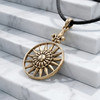 Gold sun amulet with a fleur de lis draped elegantly over bright white marble steps, emphasizing the polished bronze finish of this nature jewelry