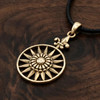 Gold Sunburst necklace at our pagan jewelry store resting flat on a rich dark wood grain surface, highlighting the detailed compass-like rays of the gold sun amulet
