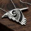 Witch familiar crow pendant in sterling silver at our pagan jewelry store, displaying an intricate Celtic spirit animal design resting on a dark wood grain surface