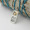 Sagittarius necklace and zodiac charm in sterling silver and gold vermeil propped against a bundle of white sage