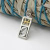 Artistic shot of a Pisces pendant at our pagan jewelry store resting against a bundle of dried sage bound with blue string, highlighting its spiritual theme