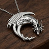 Large dragon pendant resting on a dark wood grain background, an impressive sterling silver dragon necklace showcasing a mythical beast curled on a crescent moon