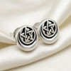 Moon pentacle stud earrings resting on a piece of shimmering white silk fabric