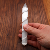 Hand holding a glowing Selenite spiral wand for directing energy and removing blockages.