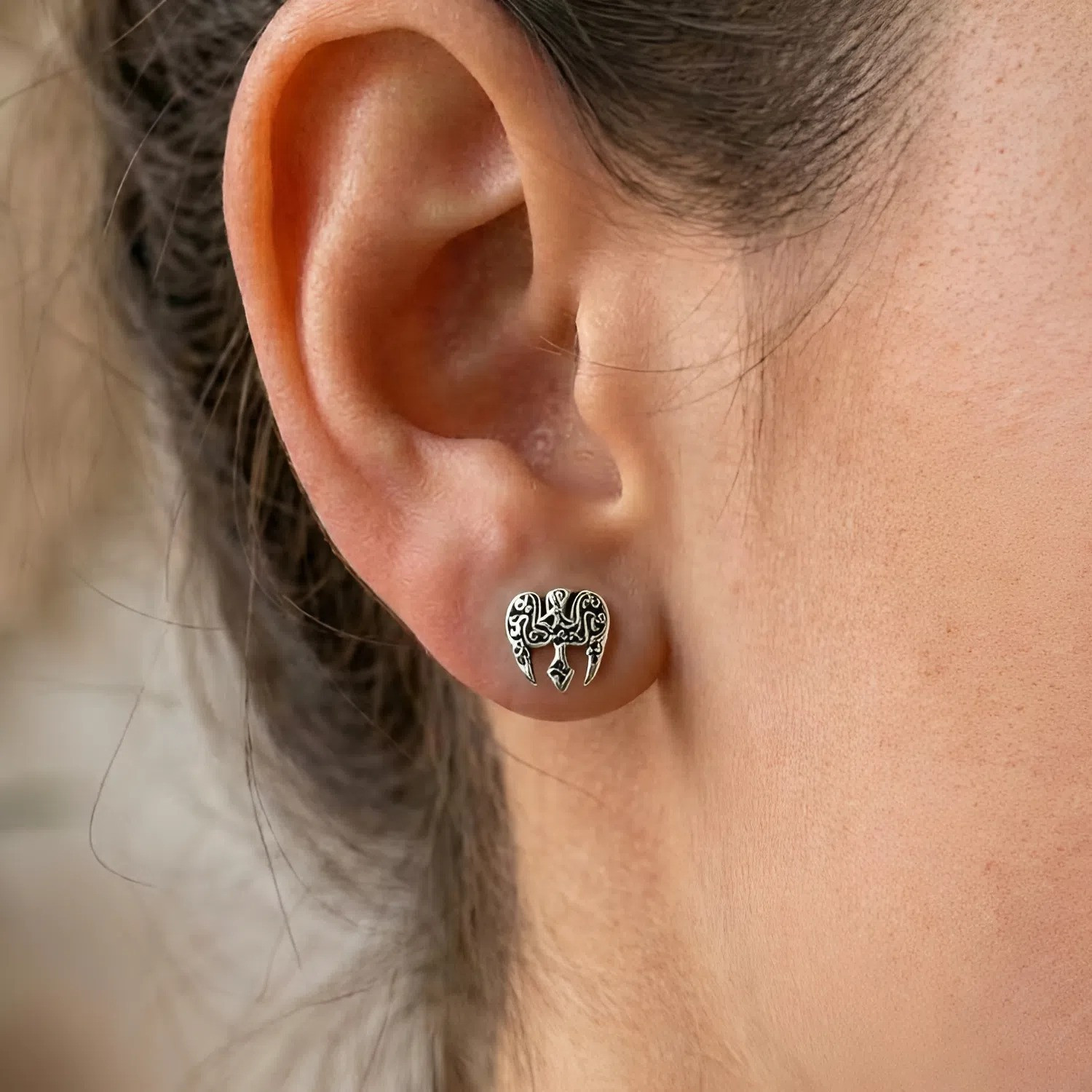 Celtic raven stud earrings: Close-up of a silver knotwork bird earring worn comfortably on a woman's earlobe