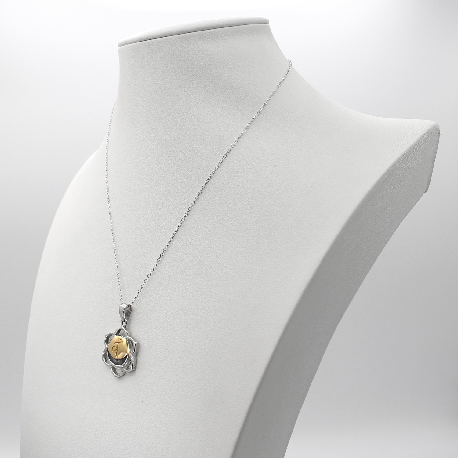 Chakra pendant for the Sacral Chakra resting on a dark wood surface to show the silver and gold contrast