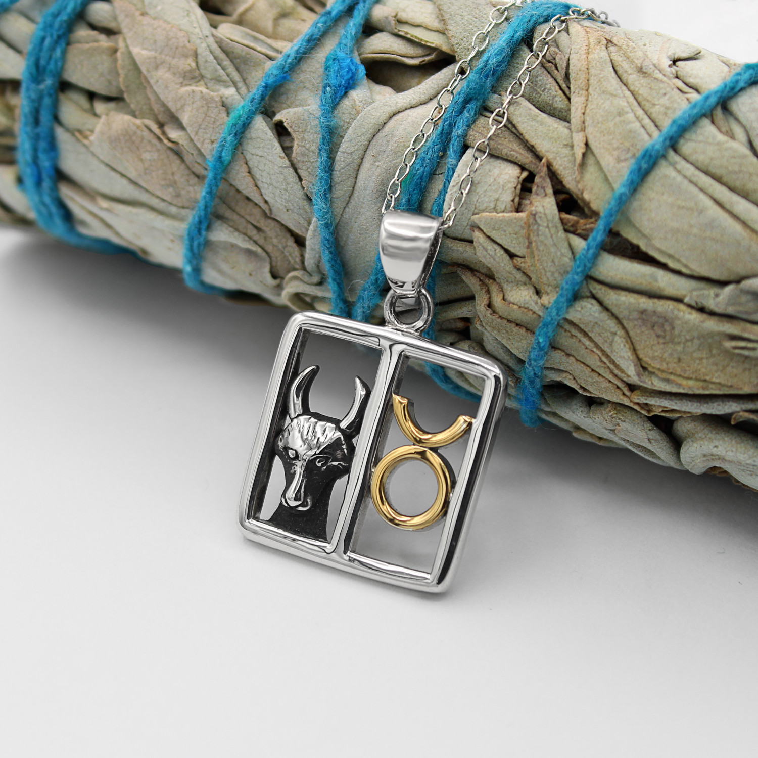 Mystical Taurus necklace draped elegantly over a bundle of dried sage, showcasing the fine .925 sterling silver and gold craftsmanship