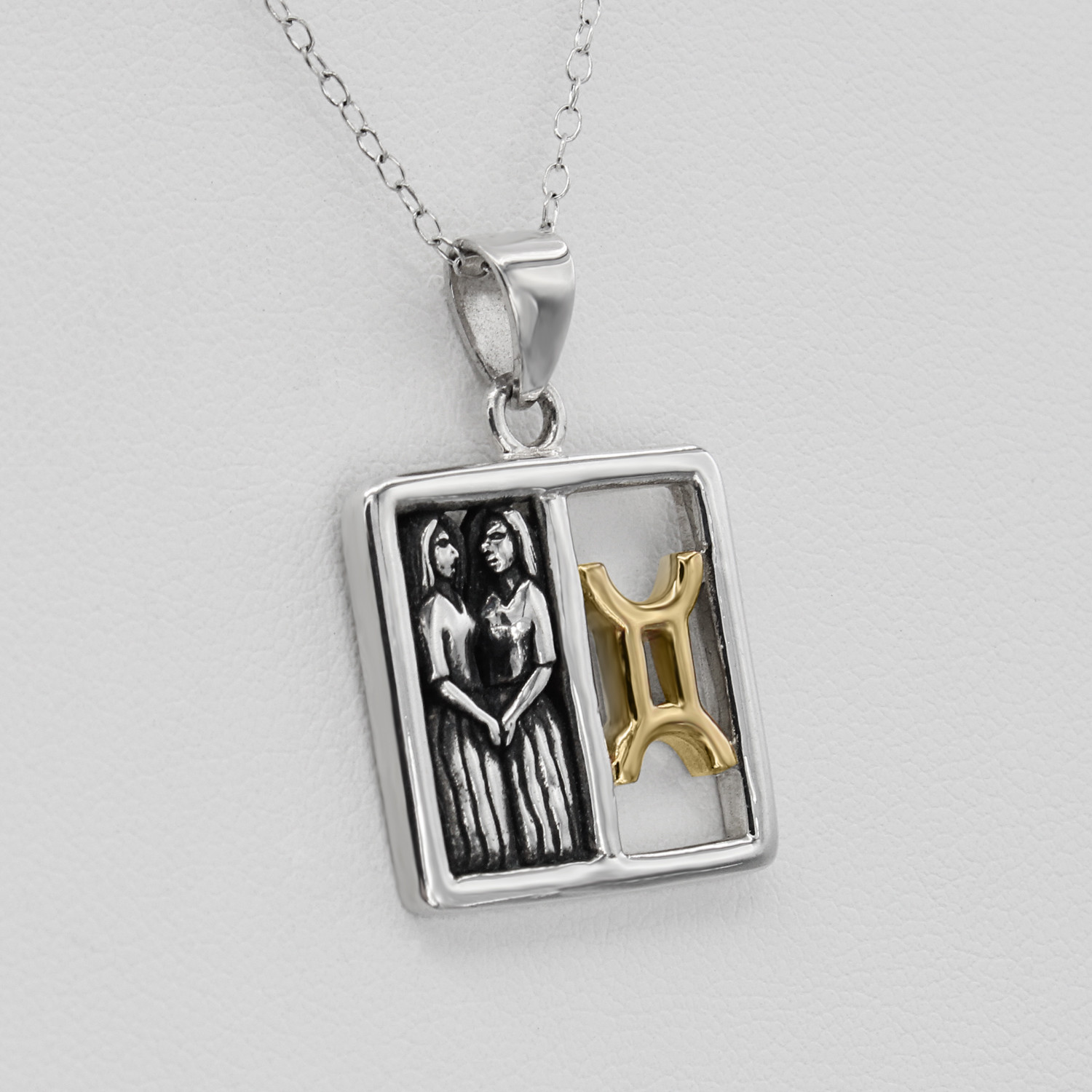 Gemini necklace horoscope jewelry featuring a balanced split-window design with three-dimensional silver twins and a polished gold Gemini symbol