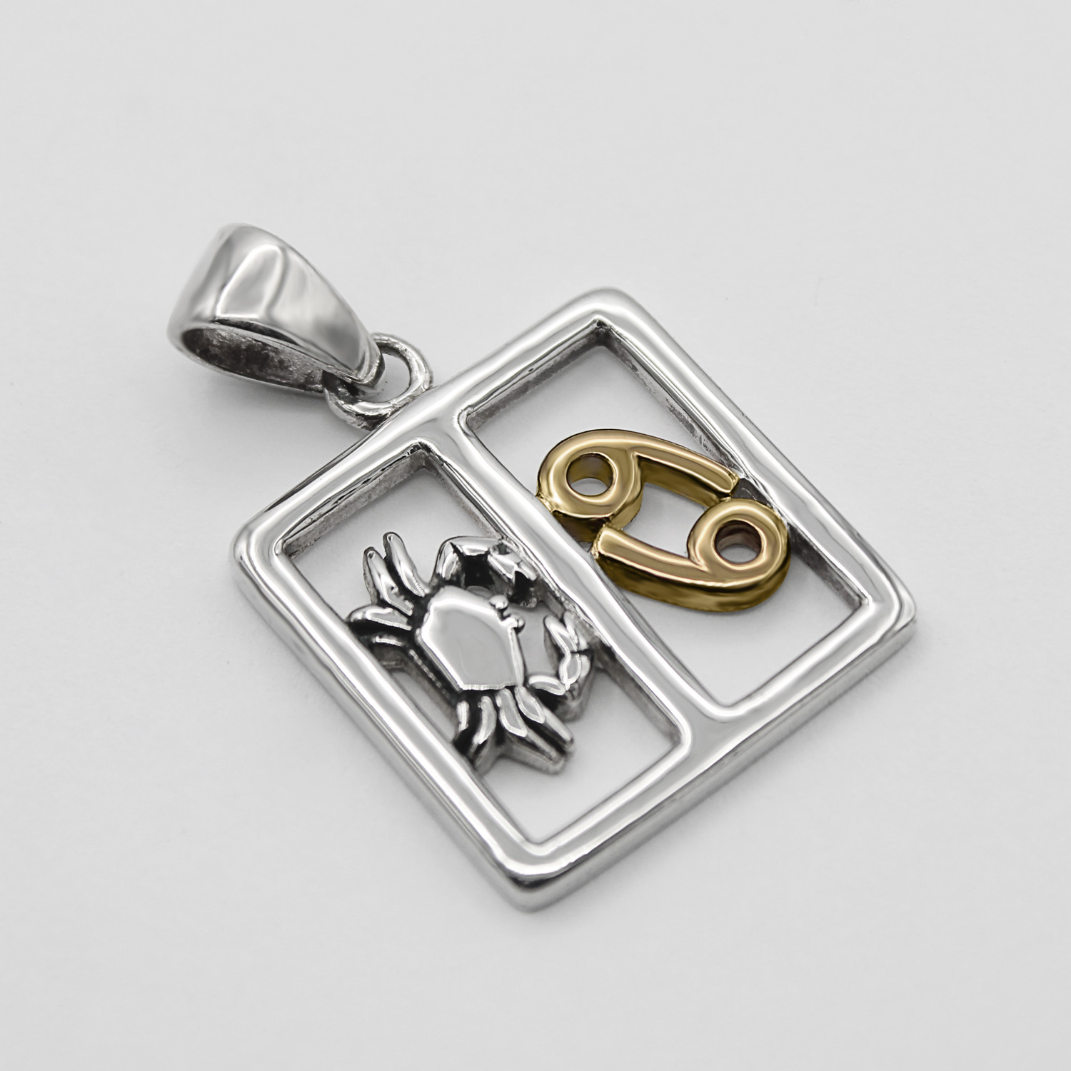 Cancer pendant zodiac necklace highlighting the intricate silver detailing of the crab figure alongside the brilliant gold astrological sign, lying flat against a pristine background