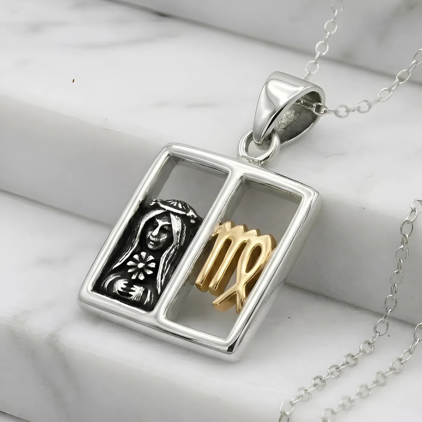 Virgo pendant zodiac jewelry, displaying a two-tone silver and gold horoscope design resting elegantly on white marble steps