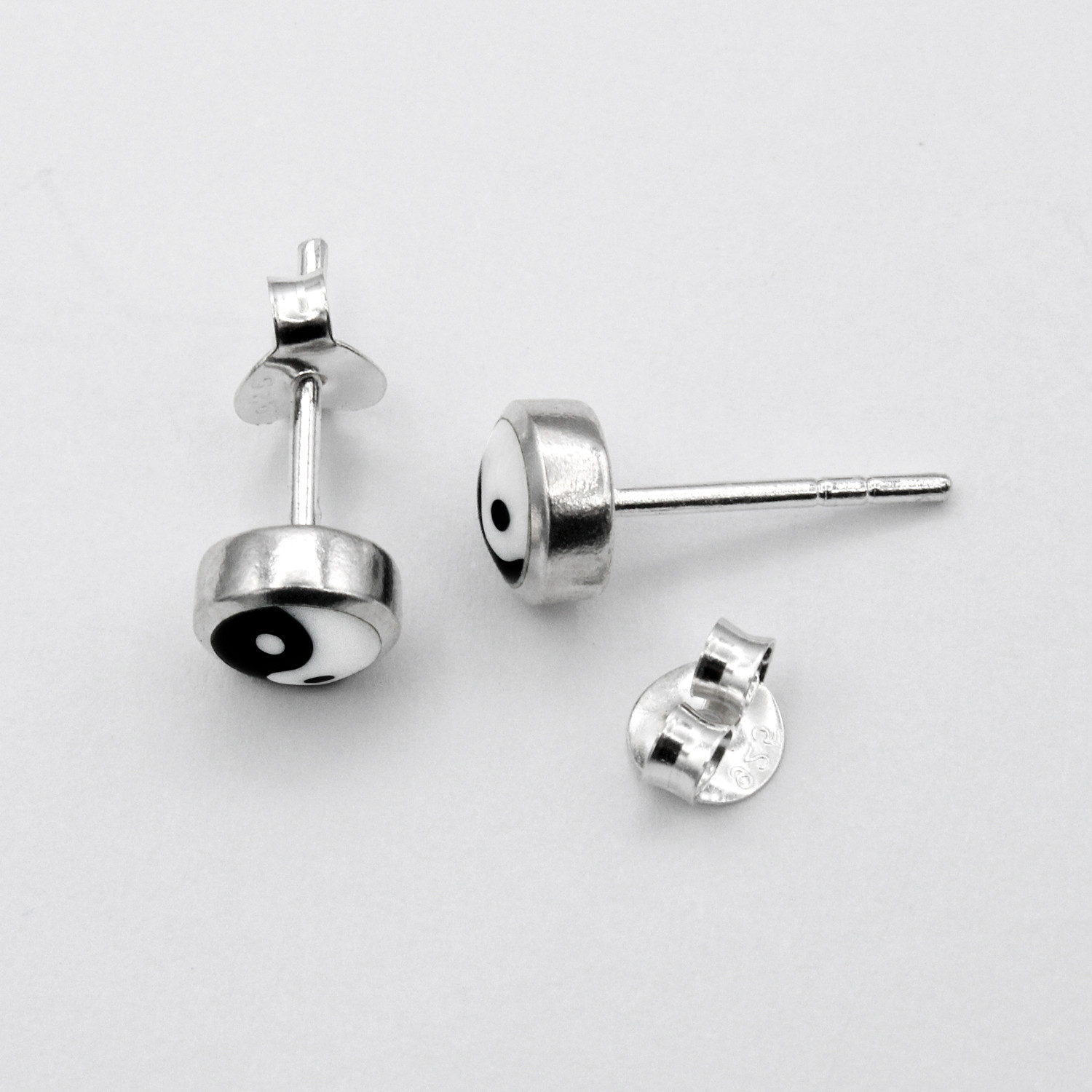 Minimalist Yin Yang earrings for women, small .925 sterling silver studs capturing the balance of black and white resting delicately on white silk