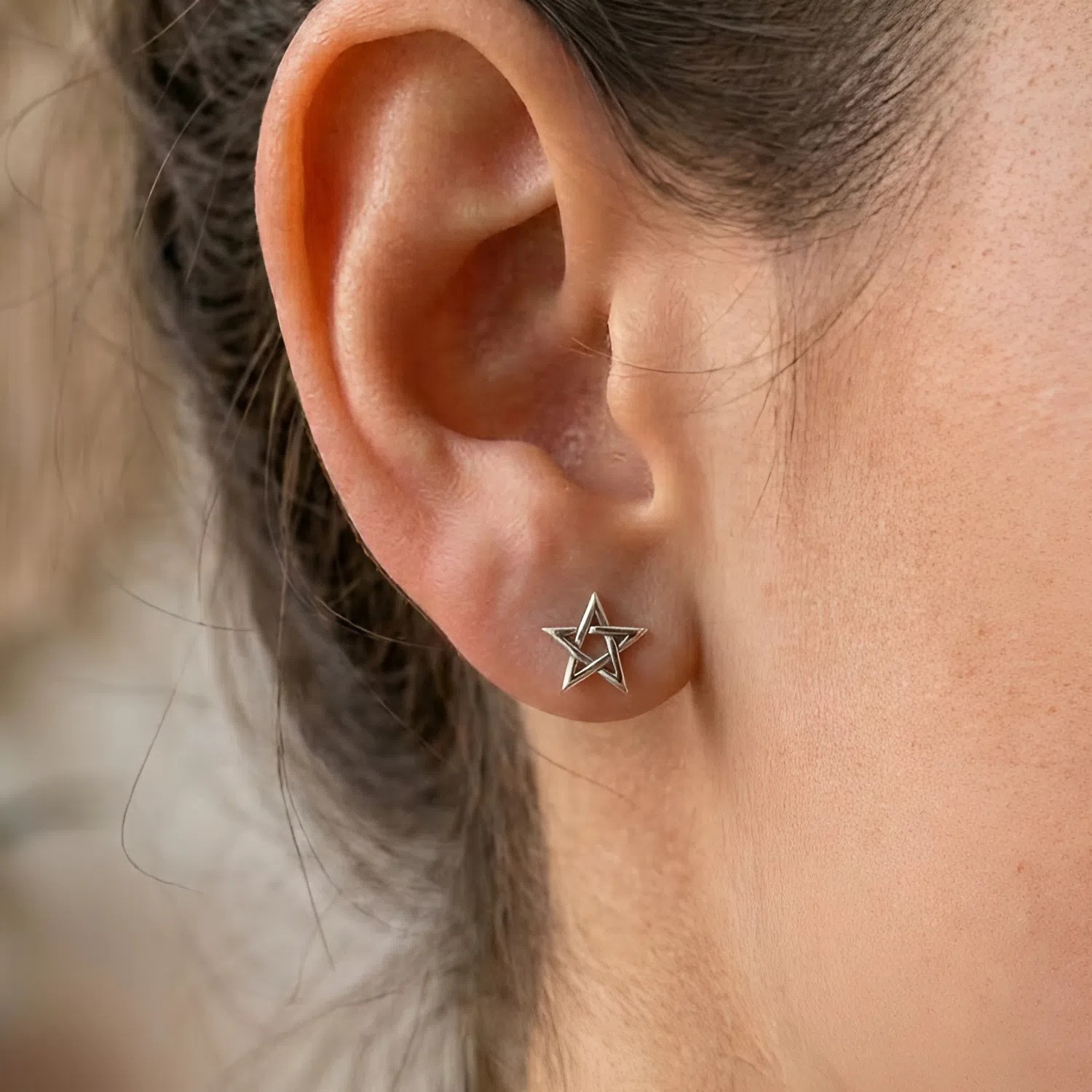 Pentagram studs in premium sterling silver, a tiny star design worn comfortably on a model's earlobe for a minimalist, mystical look