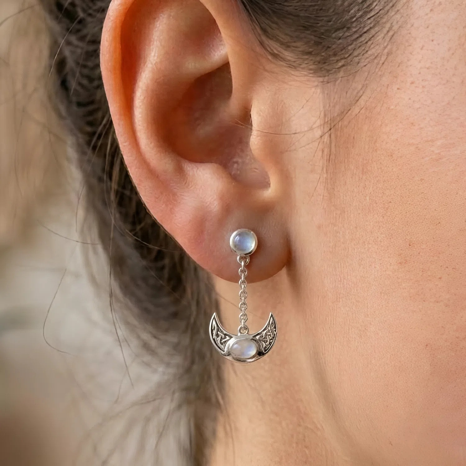 Moon and star earrings in a post-style design, emphasizing the mystical combination of a glowing moonstone