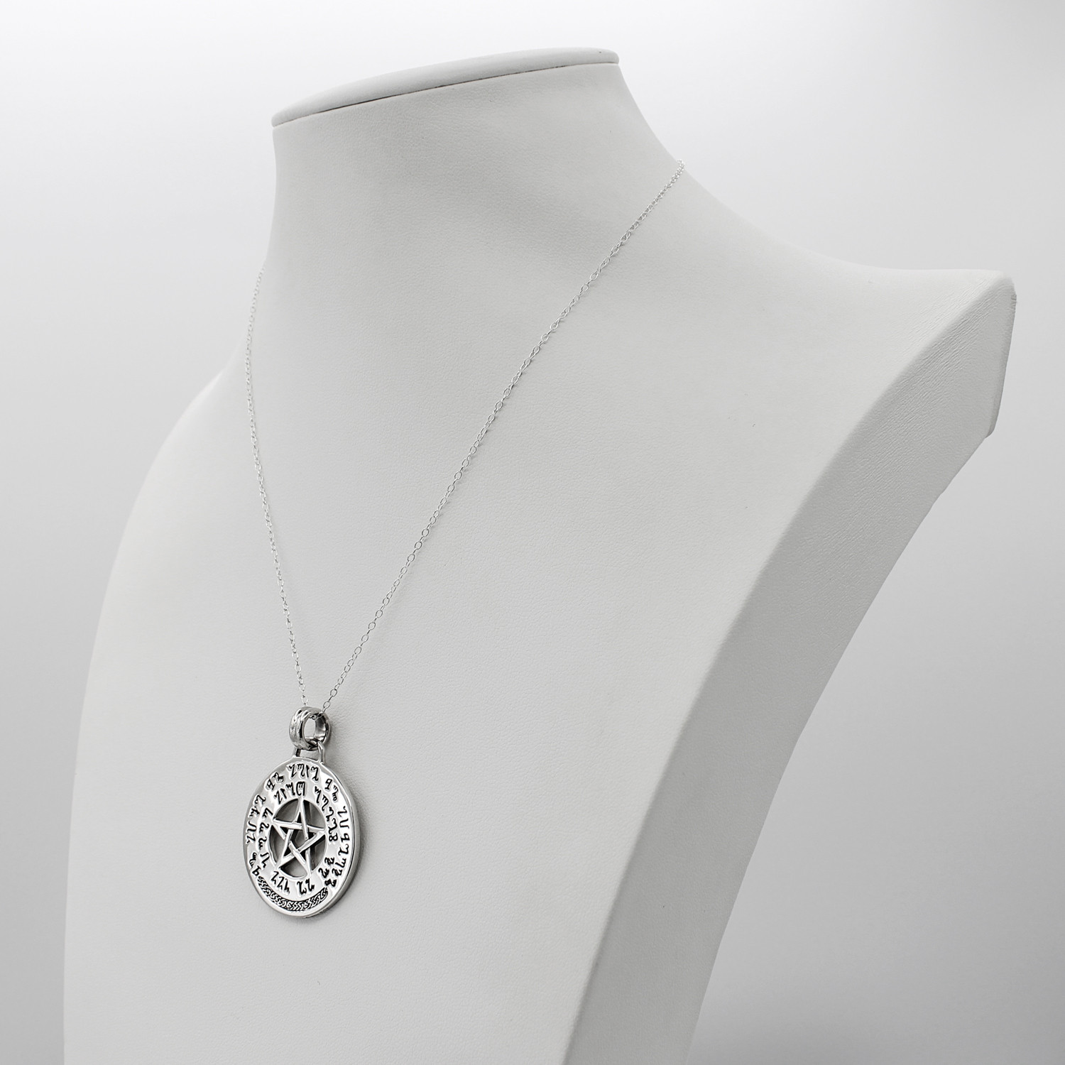 Good luck talisman amulet with a central pentacle, shown on a white display bust as a sterling silver Wiccan necklace