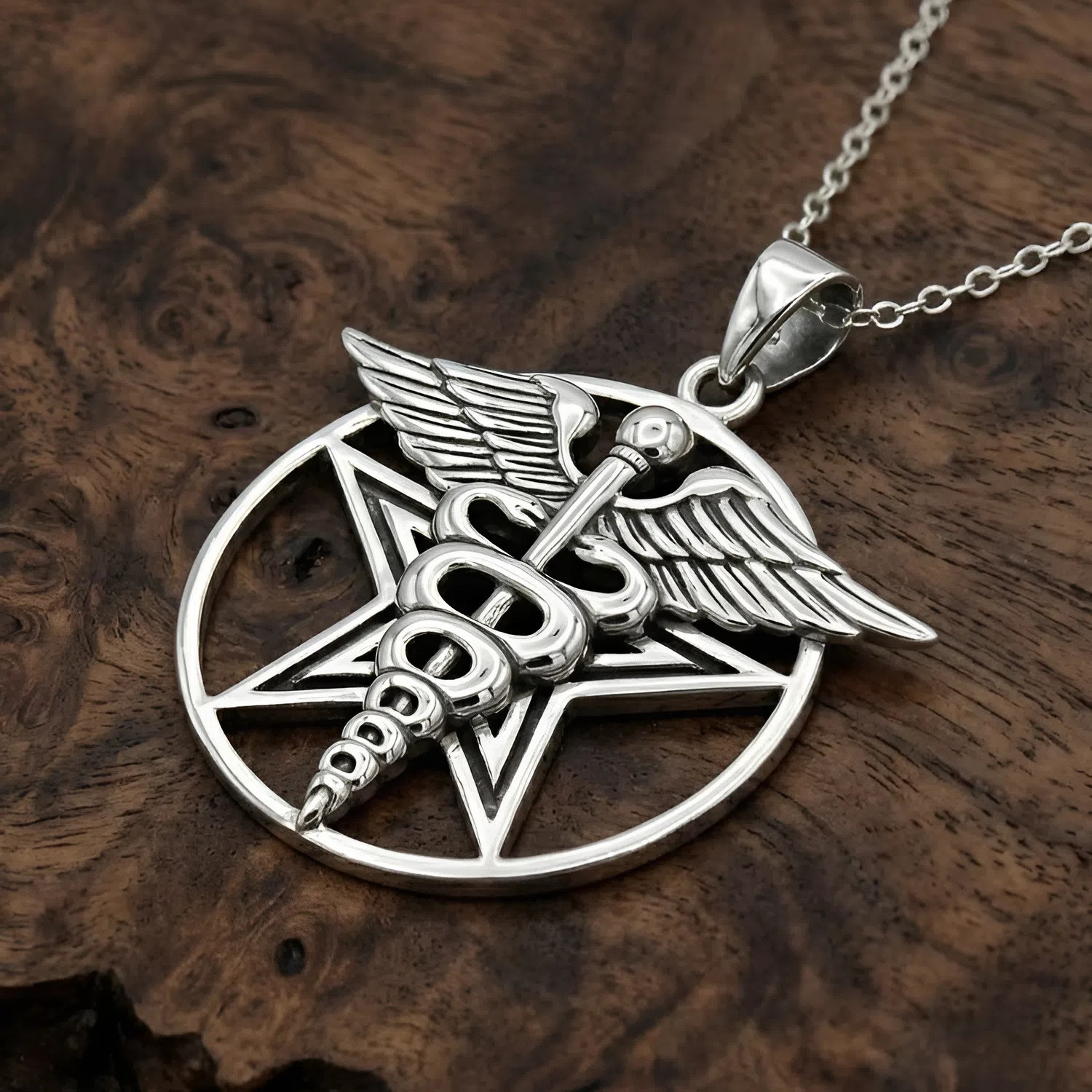 Caduceus pendant and pentacle pendant in solid sterling silver, a beautiful healers pentagram and amulet resting gracefully on a dark wood background