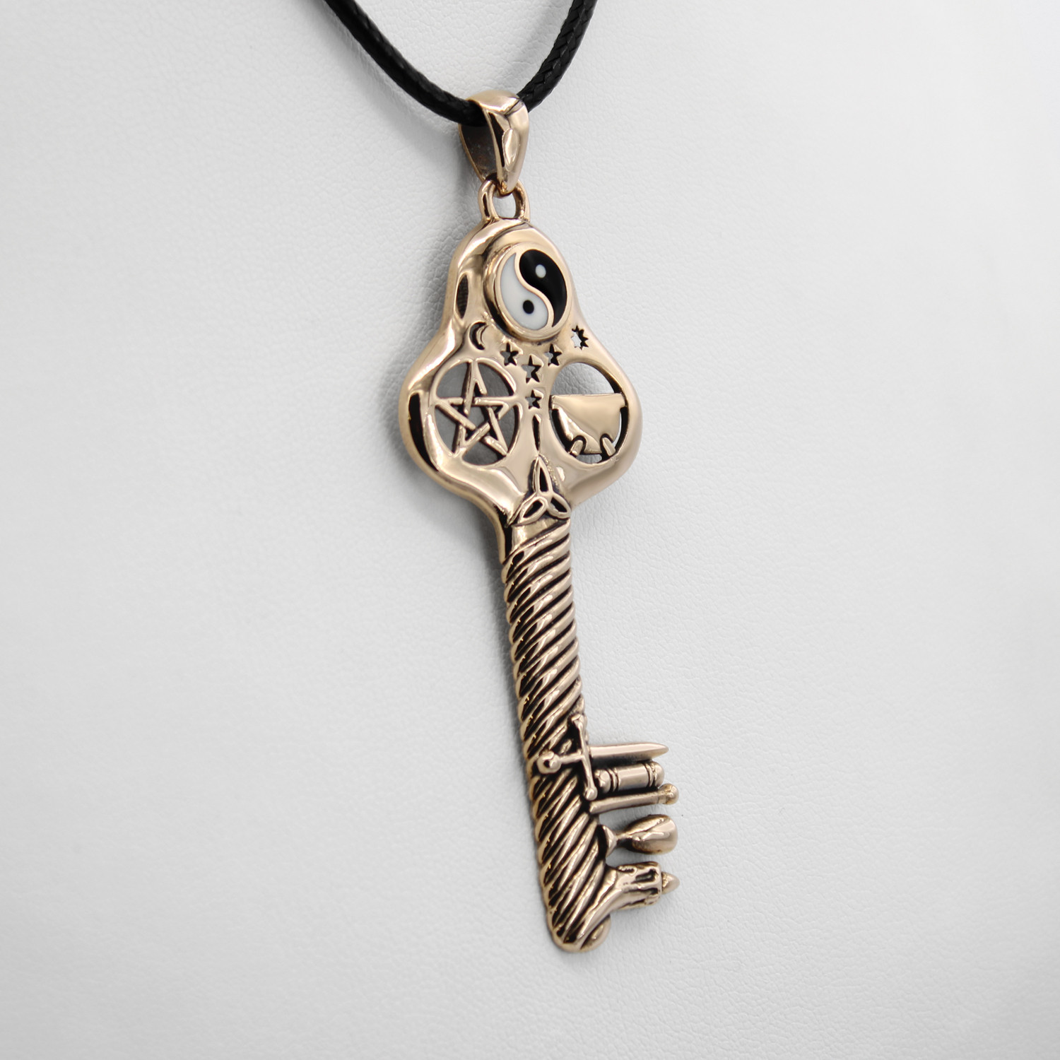 Wicca jewelry featuring a large magic key pendant, close-up angled to the left, showcasing the textured bronze shaft and witchy symbols