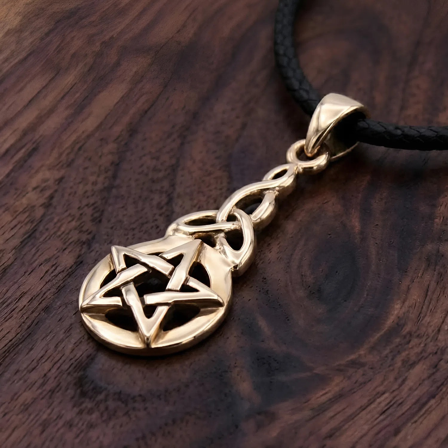 Triquetra pentacle pendant lying flat on a rich dark wood grain surface, emphasizing the highly reflective, glowing finish of this pagan jewelry