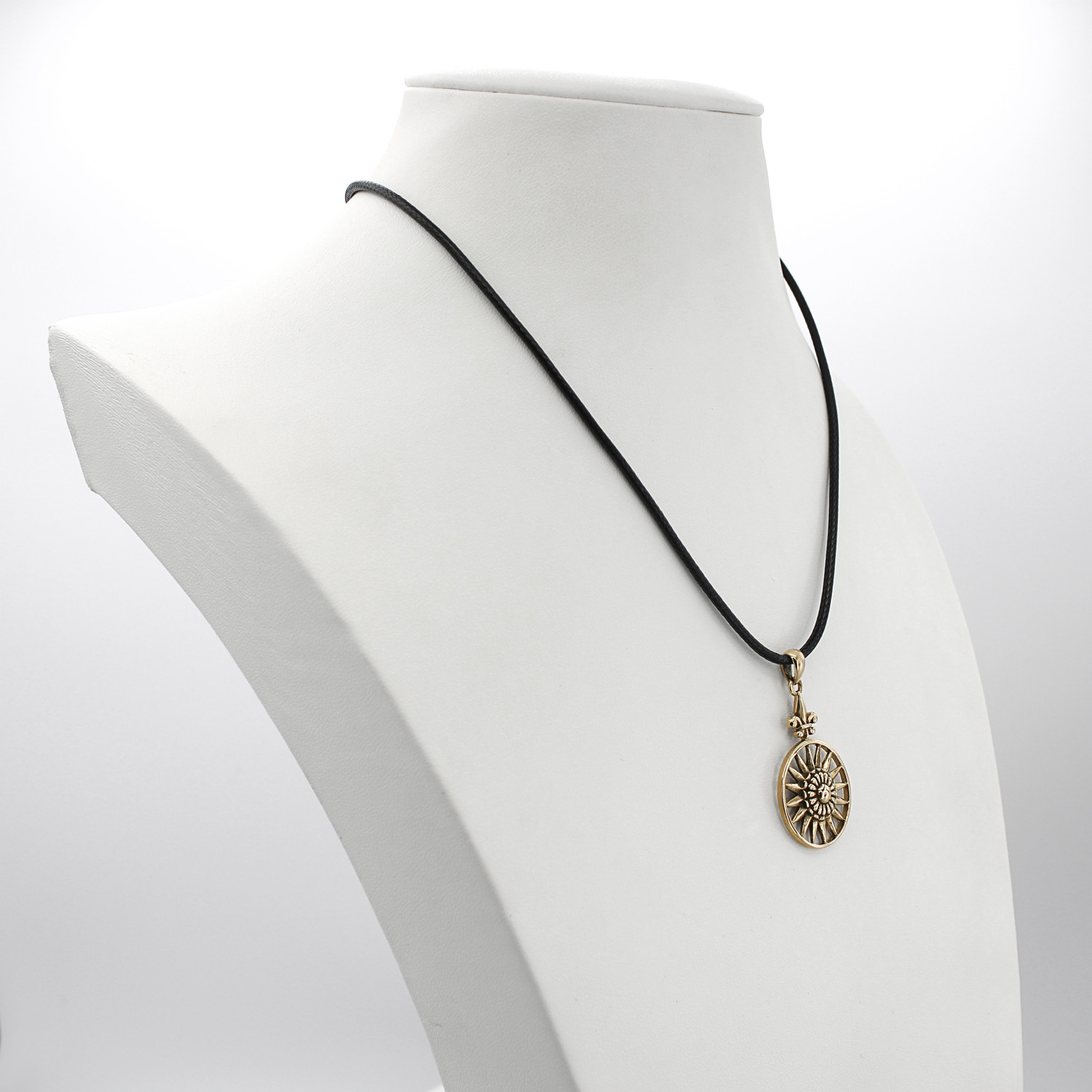Bronze Sun pendant displayed on a white jewelry bust at our pagan store, demonstrating the hanging scale and black cord of this beautiful gold sunburst necklace