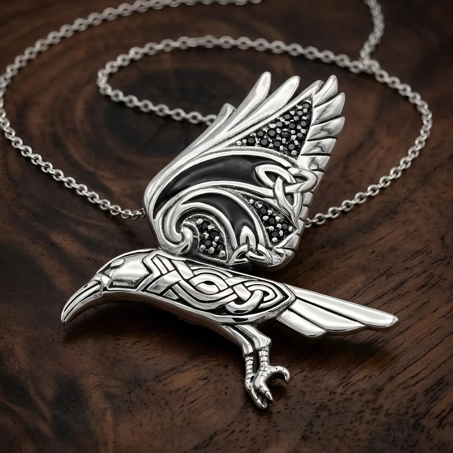 Witch familiar crow pendant in sterling silver, displaying an intricate Celtic raven spirit animal design resting on a dark wood grain surface