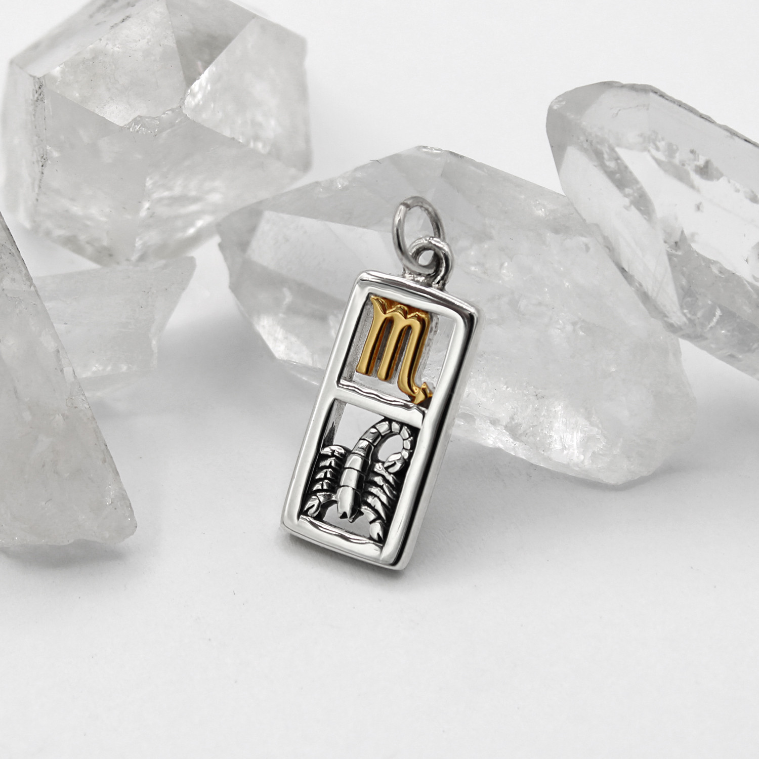 Scorpio necklace and zodiac charm at our wicca jewelry store in sterling silver and gold vermeil leaning against clear quartz crystals