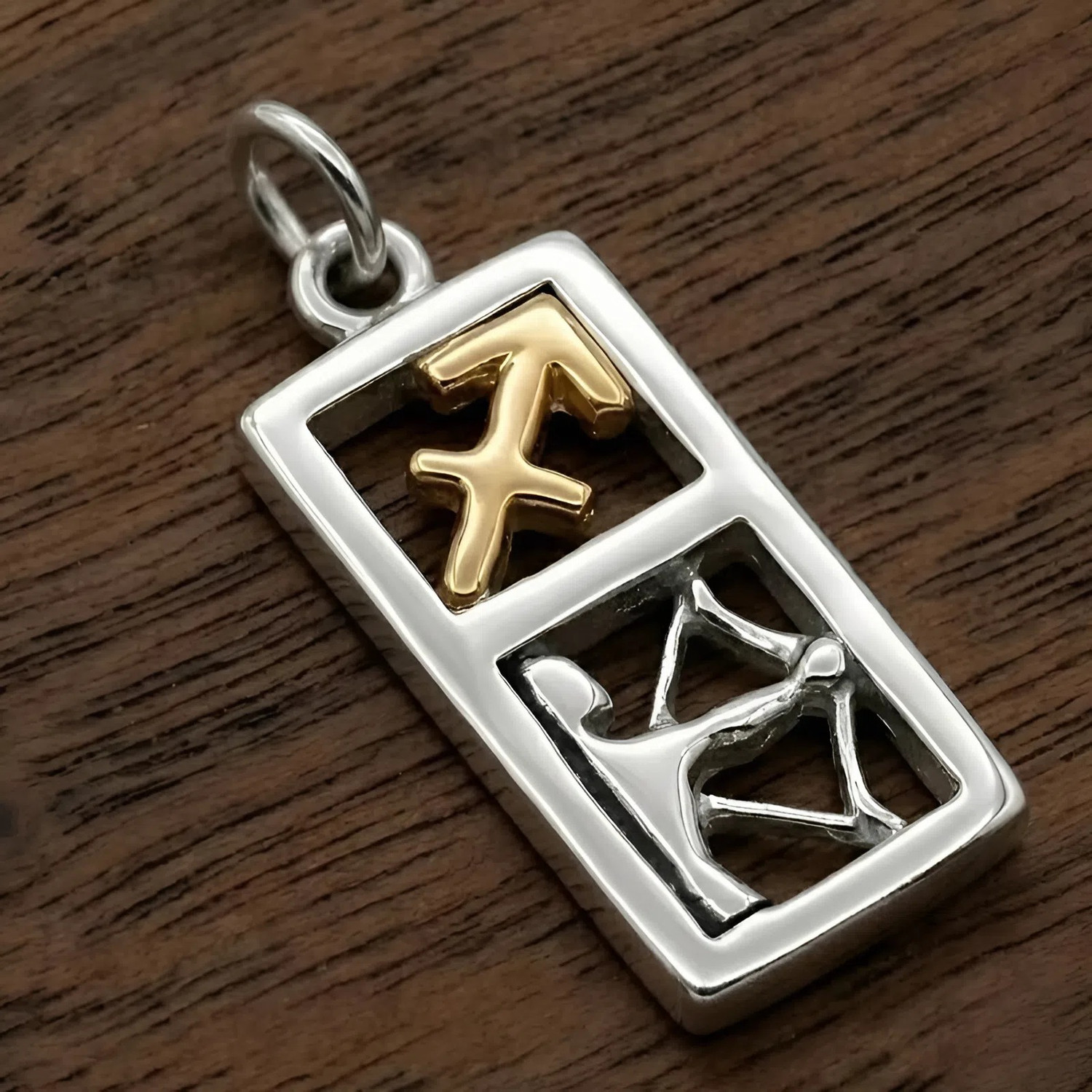 Sagittarius pendant at our jewelry shop in .925 sterling silver and 14k gold vermeil featuring a detailed archer and arrow symbol on a dark wood background