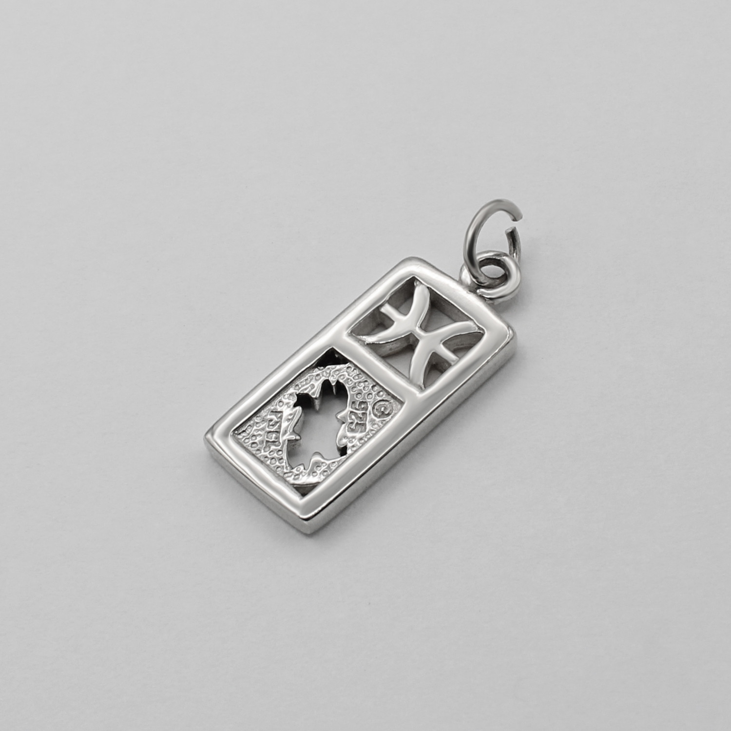 The back side of a sterling silver Pisces pendant, displaying the textured metalwork behind the fish cutouts and the .925 hallmark stamp