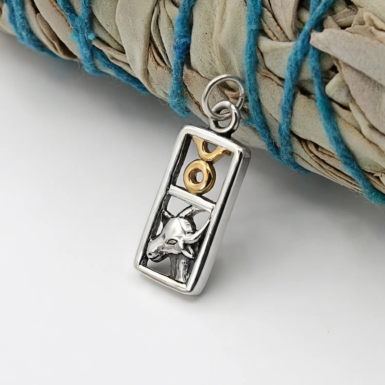 Detailed view of the silver bull head and gold-toned Taurus symbol set within a polished rectangular silver frame