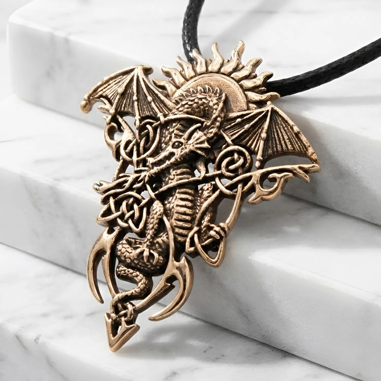 Gold dragon necklace resting elegantly across white marble steps, highlighting the intricate Celtic knotwork and outstretched wings of the rising sun dragon pendant