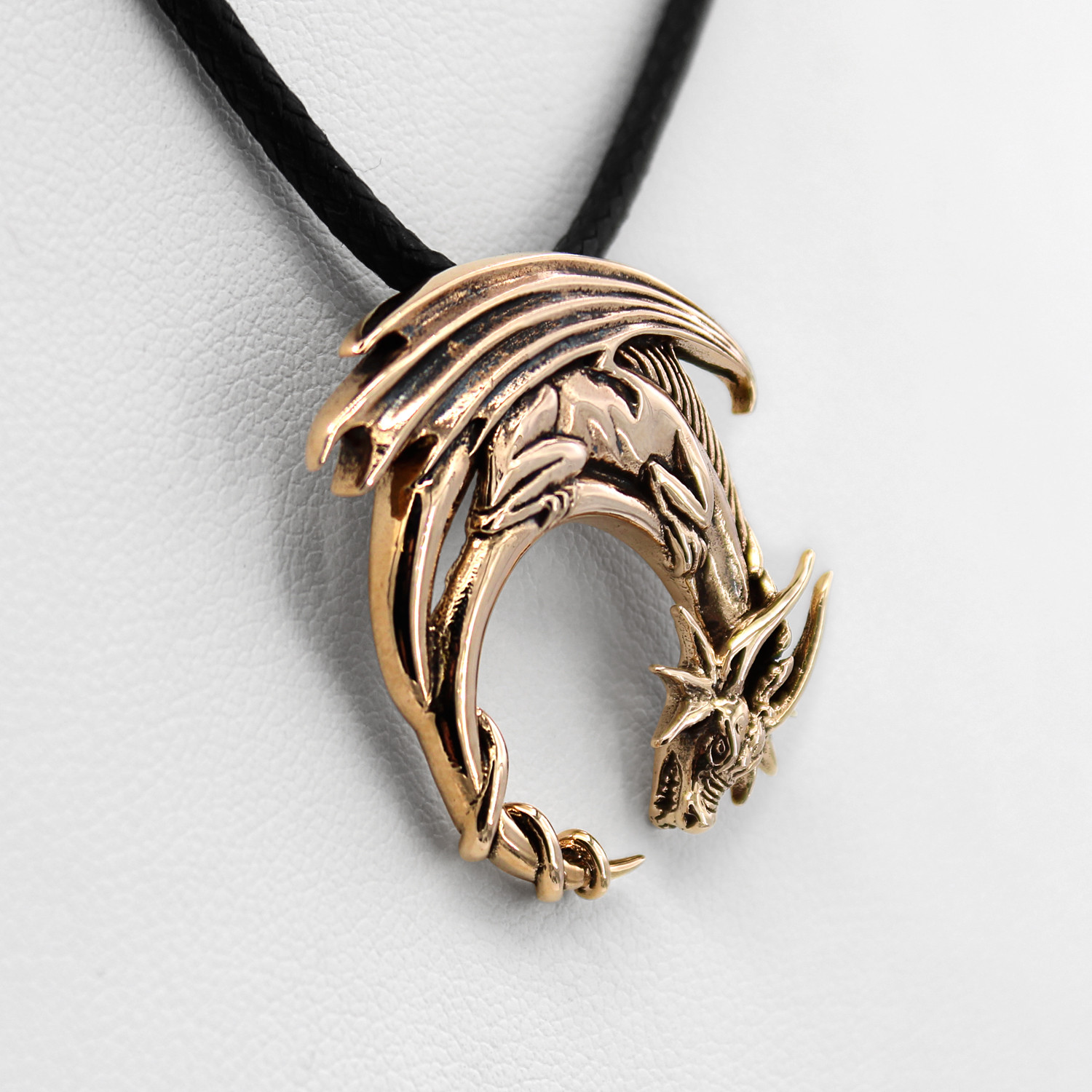 Bronze dragon pendant close-up angled to the right, highlighting the bright gold-colored finish and the intricately curved tail of this mythical creature necklace