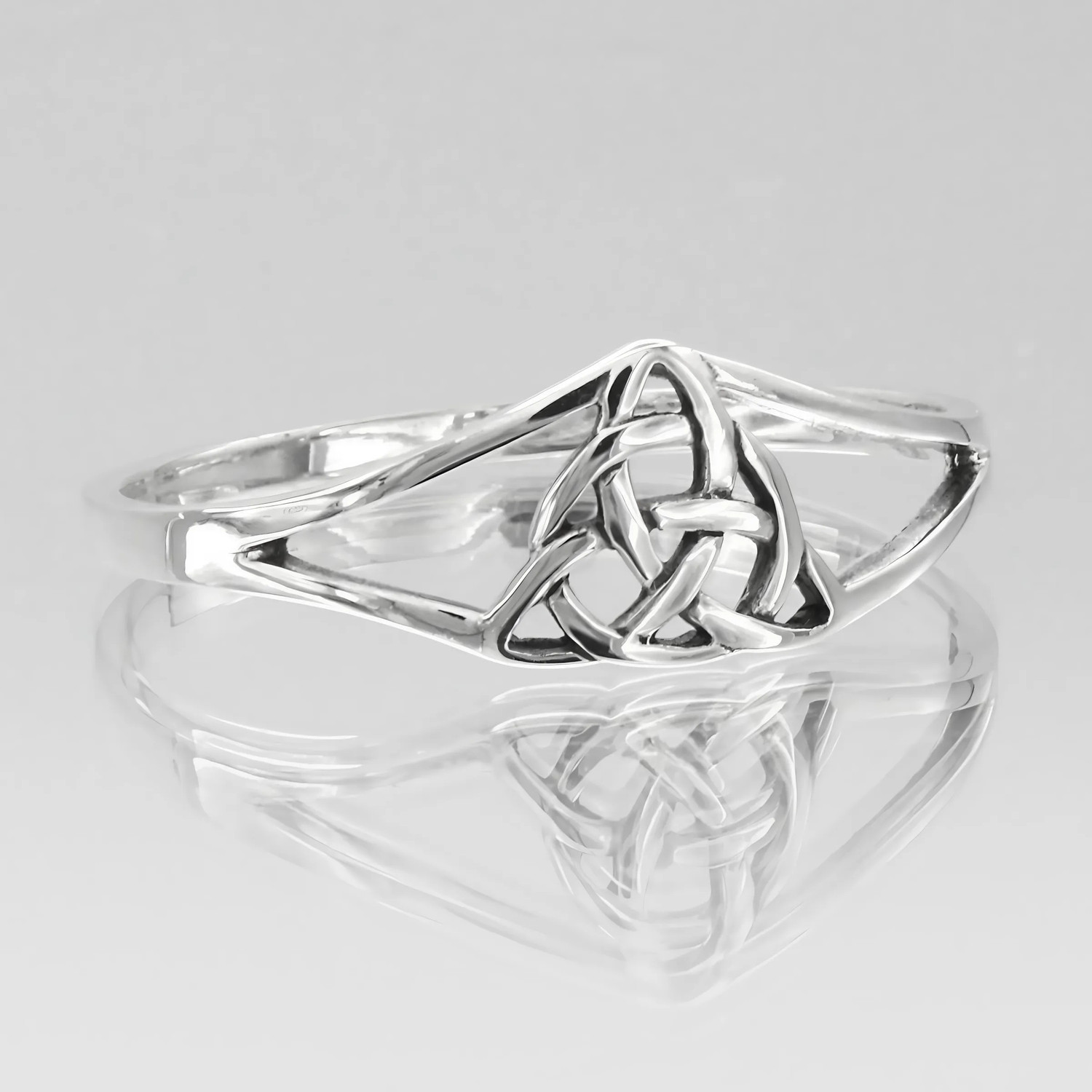 Angled view of a polished sterling silver Celtic knot triquetra ring featuring a split band