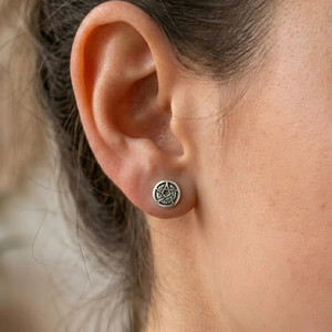 Pentagram Post earrings: Close-up of a silver crescent moon and pentacle stud earring worn on a person's ear