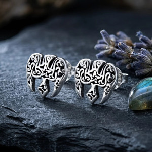 Raven pentagram earrings: Silver Celtic bird studs resting on dark slate next to dried lavender and a polished stone